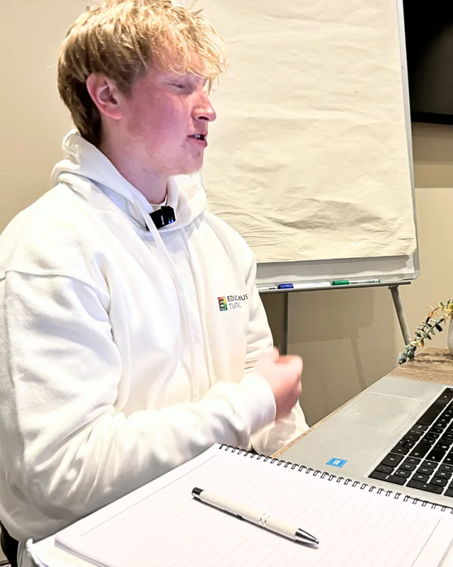 Angus, an Educamus Tuition maths tutor, teaching at a laptop in an Educamus Tuition hoodie